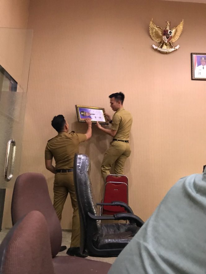 
Staff ajudan Pj Bupati Bangkalan saat menurunkan foto mantan Bupati Makmun Ibnu Fuad