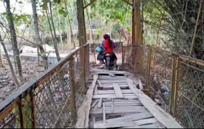 
Keterangan Foto: Terlihat warga mengendarai sepeda motor sedang melintas di jembatan gantung di Dusun Kacodur, Desa Daleman, Kecamatan Kedungdung.